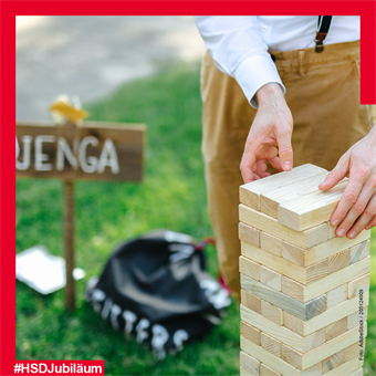 Riesen-Jenga: Ein junger Mann spielt Jenga in Lebensgröße