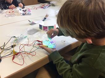A group of children discovers the principles of direct current and alternating current using LED plug-in systems.