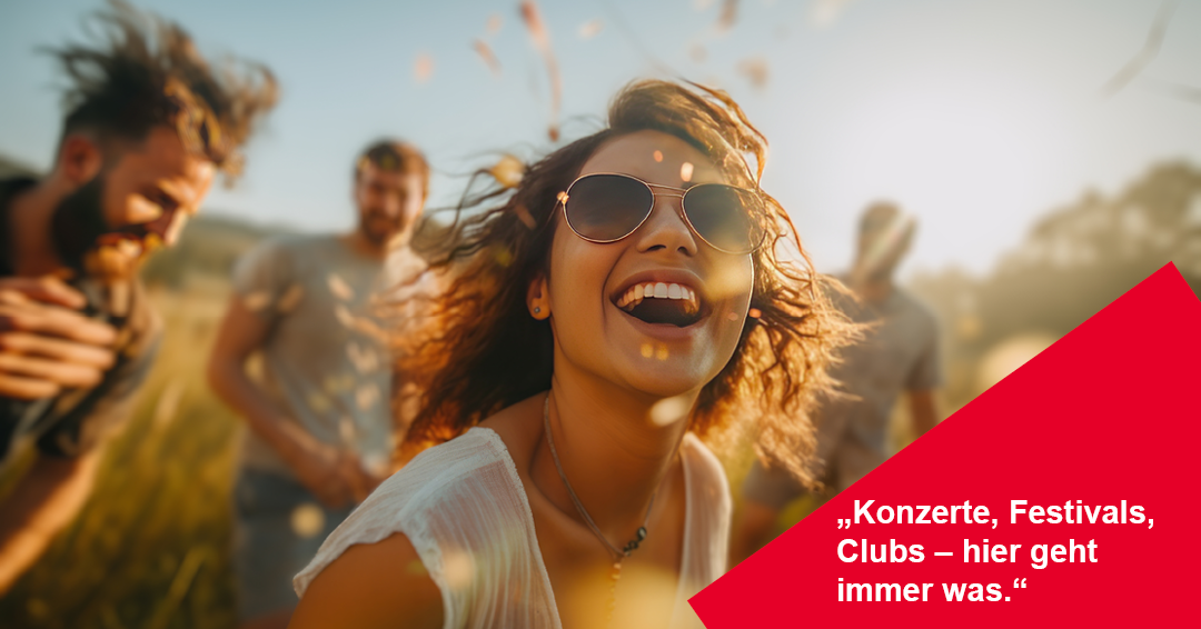 Eine fröhliche Nahaufnahme einer jungen Frau mit Sonnenbrille und wehendem, lockigem Haar, die ausgelassen lacht und leicht nach oben blickt.