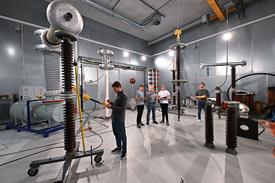 Studenten und Ingenieure stehen in einem Labor mit großen elektrischen Geräten