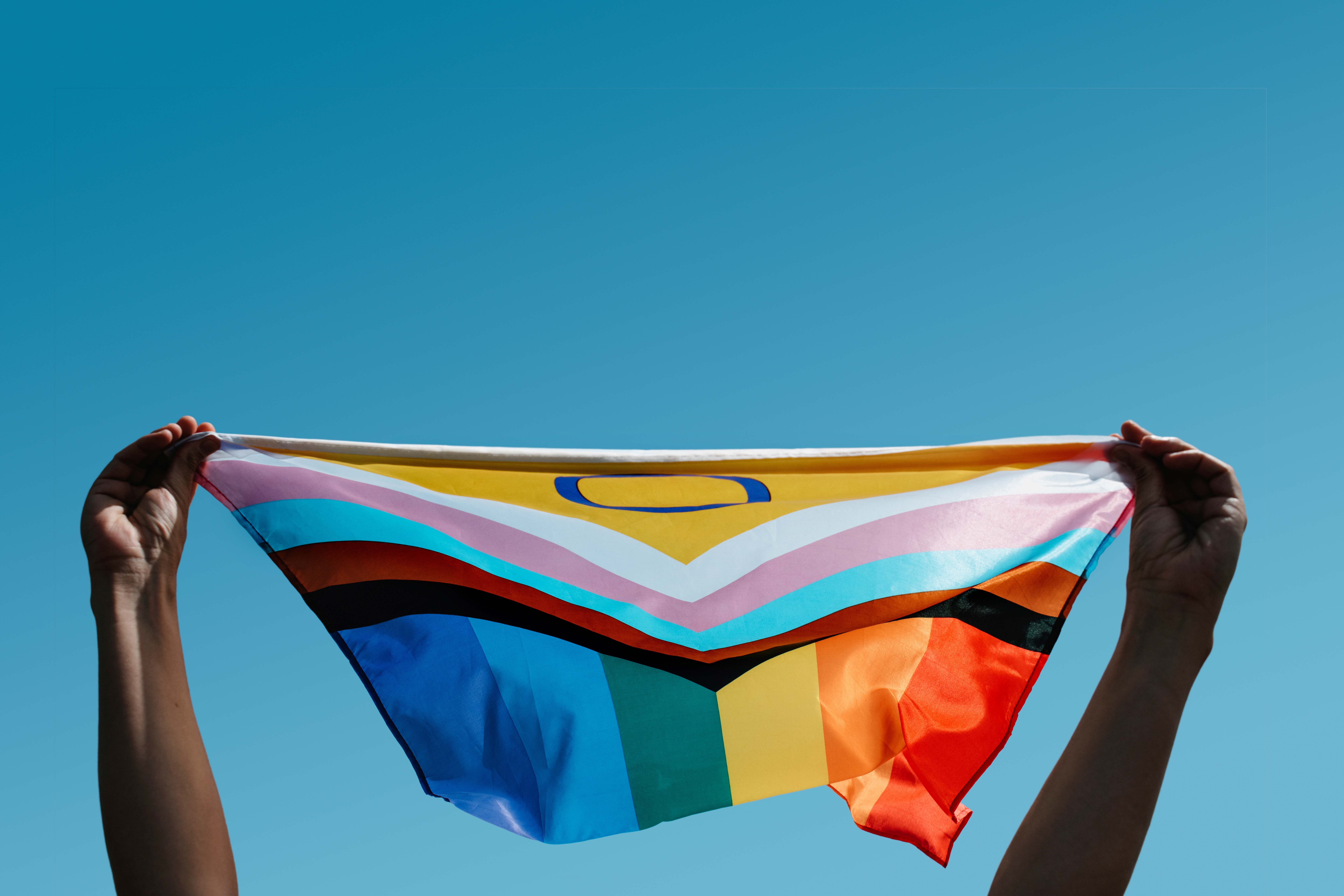 rainbow flag in front of a blue sky