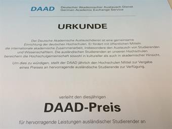 Eine Urkunde ist zu sehen, auf der groß "DAAD-Preis" zu lesen ist.