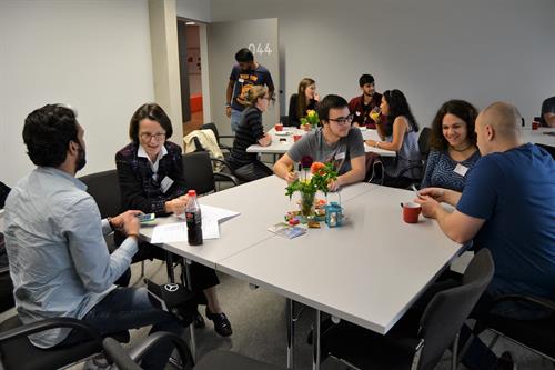 Studierende und Mitarbeiterinnen des International Office sitzen bei Kaffee und Kuchen zusammen