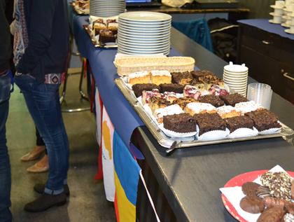 different sorts of cake placed on a bar, below it there are colourful country flags 